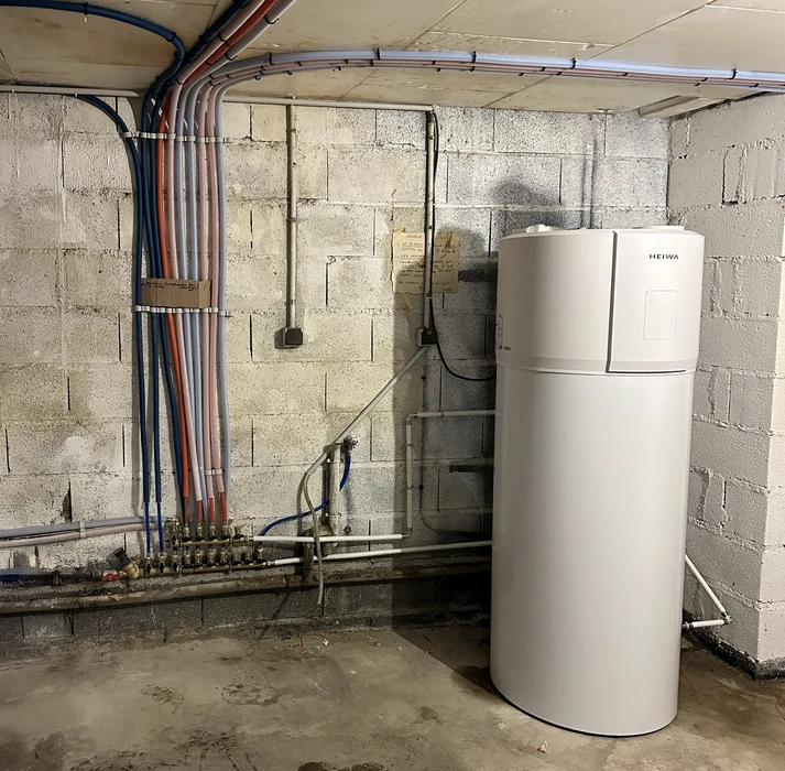 Une main tient une clé à molette pour serrer un raccord de plomberie sur des canalisations cuivre