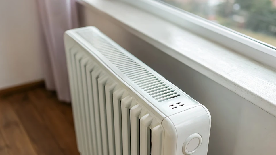 Un plombier travaille sous un &eacute;vier de cuisine, utilisant une cl&eacute; &agrave; pipe rouge pour serrer des raccords de plomberie