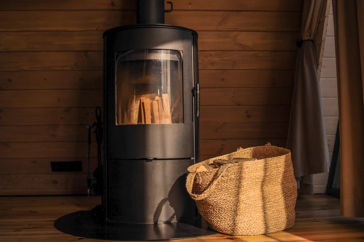 Intérieur résidentiel avec cheminée en fonte noire allumée, flammes oranges visibles à travers la vitre
