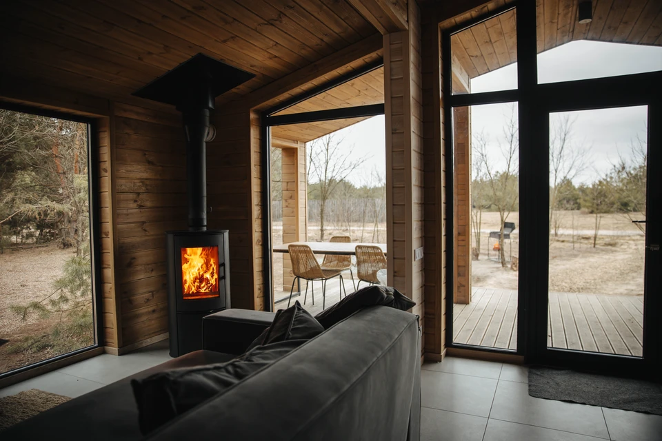 Intérieur de chalet en bois avec poêle à bois en fonctionnement, flammes visibles dans le foyer ouvert